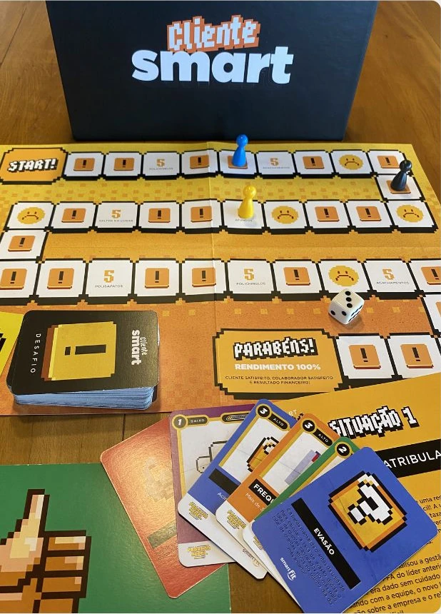 Jogo Cliente SMART com tabuleiro amarelo, peões, dado e cartas de desafios de atendimento.