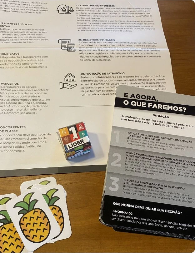 Materiais do jogo Código de Ética: orientações, cartas de situações e peças ilustradas sobre uma mesa.